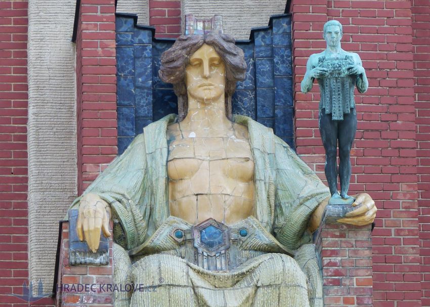 Socha v ruce drží bronzovou postavu muže symbolizujícího město Hradec Králové